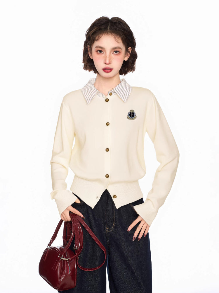 Woman wearing a cream-colored knit cardigan with a collared neckline and button-up front, holding a burgundy handbag.