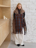 Woman standing and holding a long plaid scarf