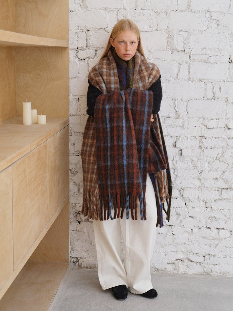 Woman standing and holding a long plaid scarf
