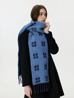 Side profile of a woman wearing a blue scarf with a black windowpane plaid pattern