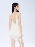 Rear view of a woman in a cream-colored mini dress with a lace-up back detail.