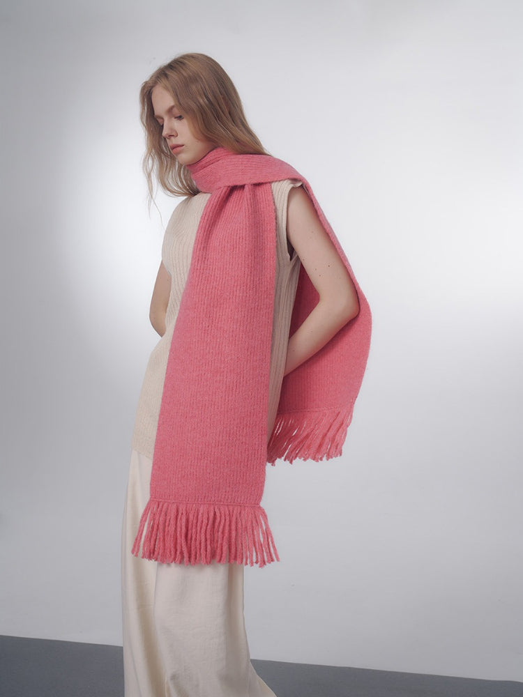 Woman wearing a pink knit scarf with fringe details