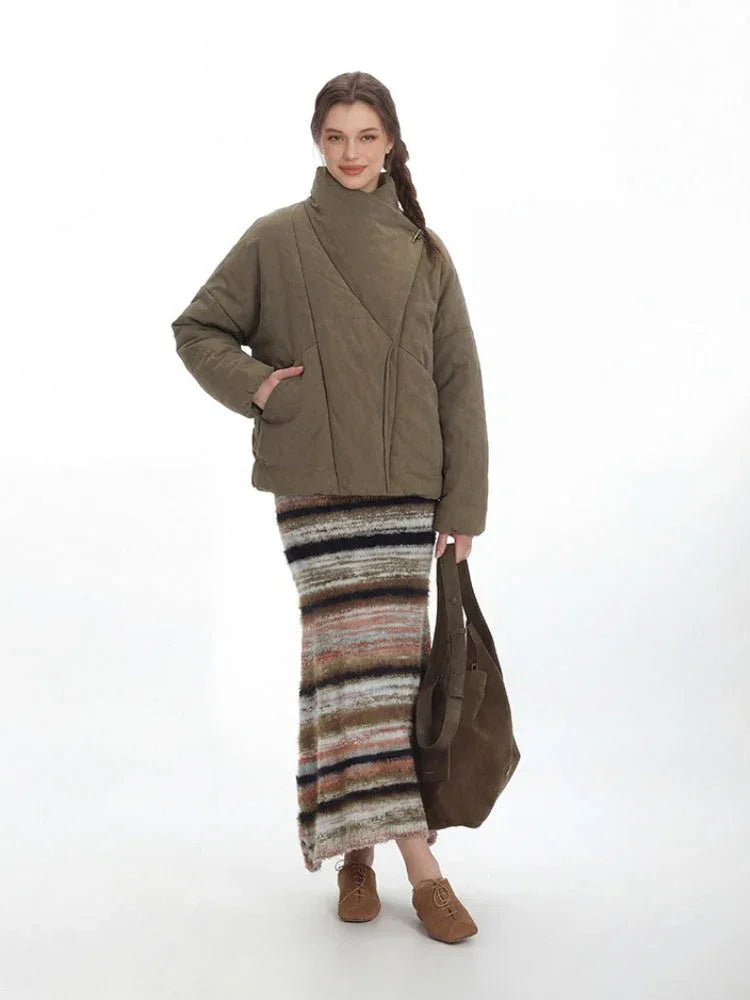 Full-length view of a woman in a cropped olive green quilted jacket and a striped maxi skirt.