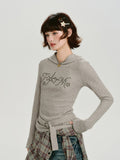 Side view of a model wearing a grey ribbed knit hooded long sleeve top with a belted waist.