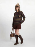 Woman posing with her hand in her pocket, showcasing a casual outfit with a striped sweater and winter accessories.