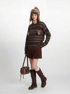 Woman posing with her hand in her pocket, showcasing a casual outfit with a striped sweater and winter accessories.