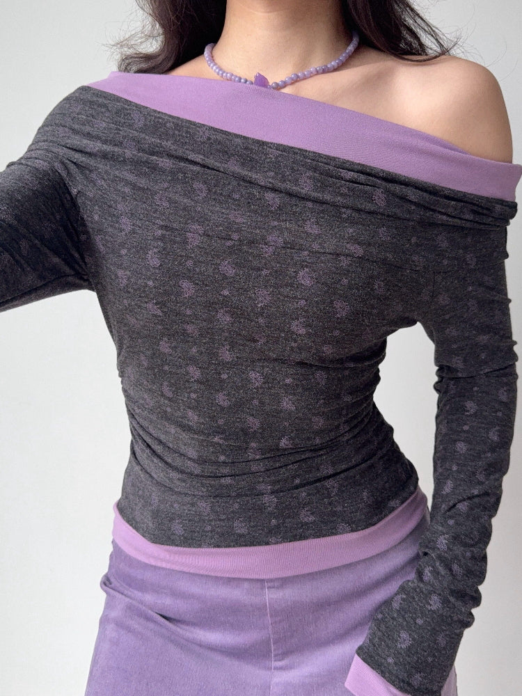 Woman wearing a grey and purple off-the-shoulder long-sleeve top with a floral print.