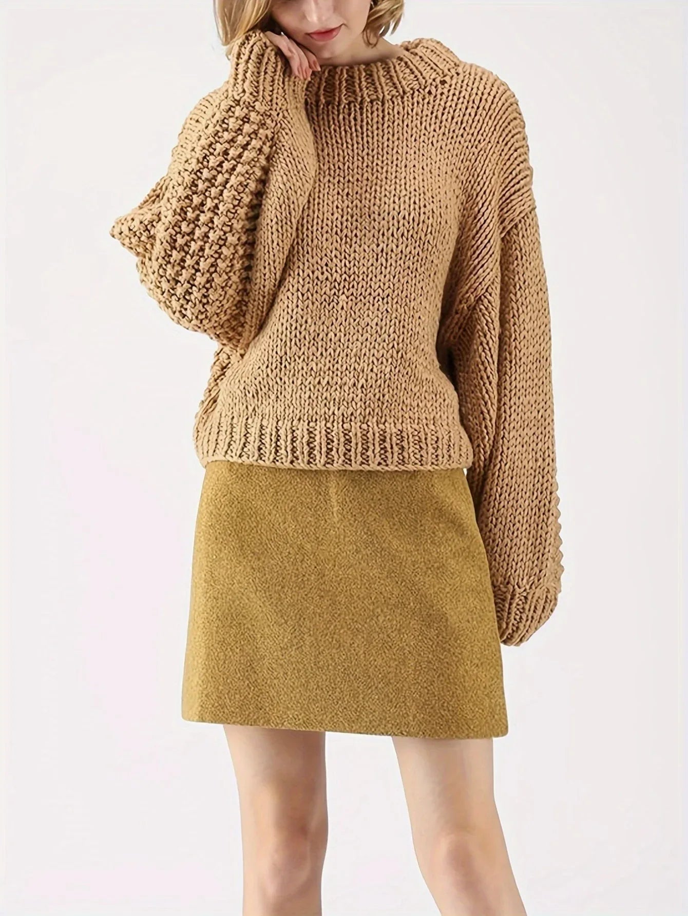 Front three-quarter view of a woman wearing a tan chunky knit sweater with balloon sleeves and a mock neckline, and a mustard yellow skirt.