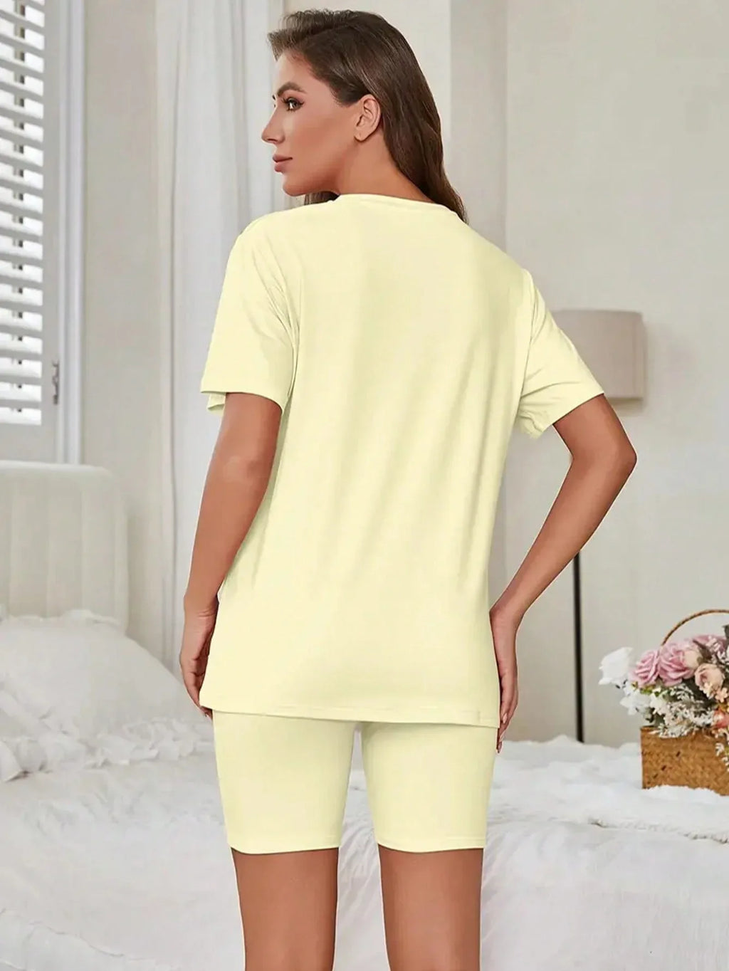 Back view of a woman in a pale yellow short sleeve t-shirt and bike shorts set.