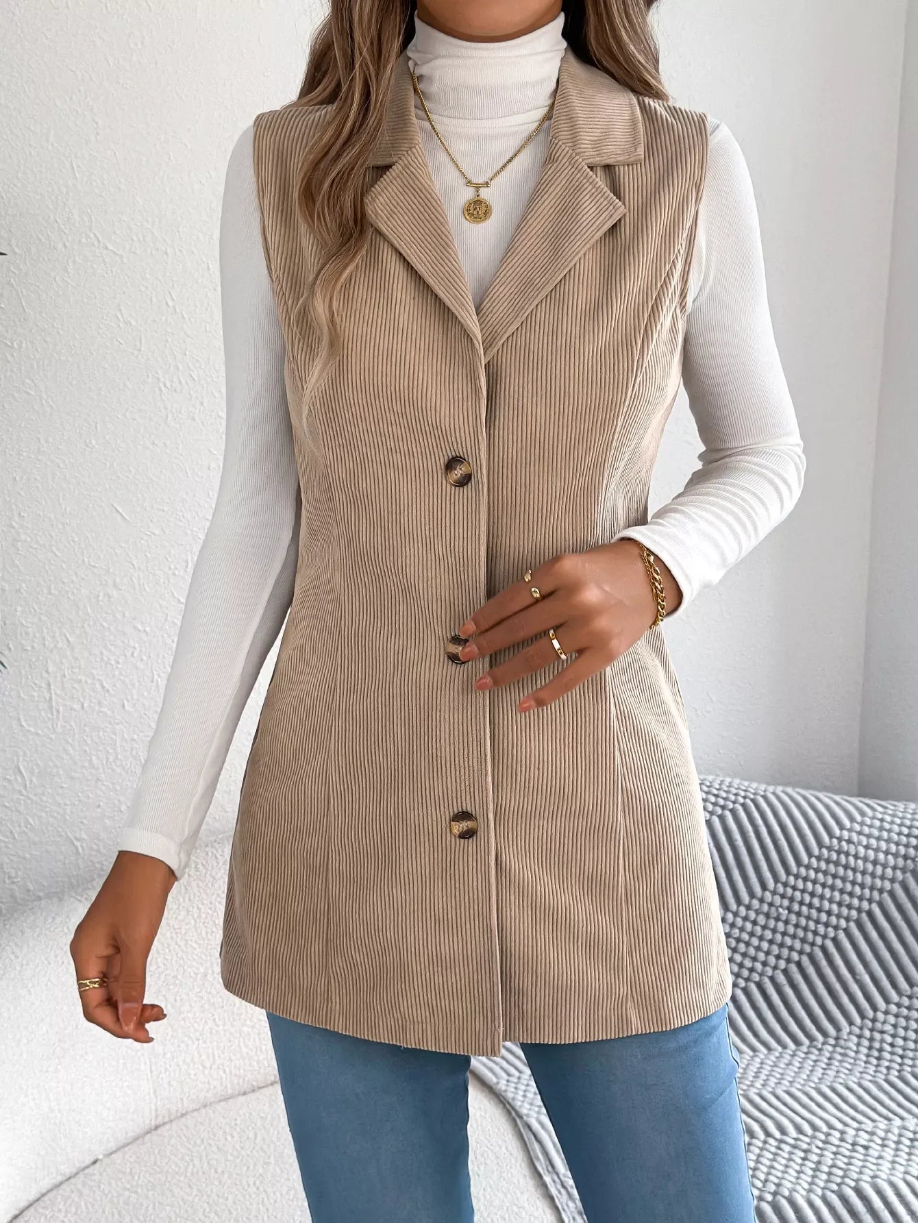 Close-up of the button detail on a beige corduroy longline vest.