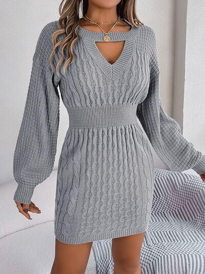 Woman wearing a grey cable knit mini dress with a cutout V-neck and bishop sleeves.