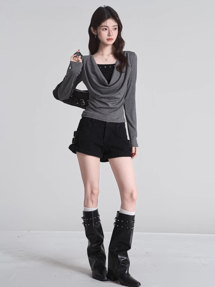 Full body shot of woman in grey draped cowl neck long sleeve top, black shorts, and black boots