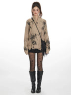 Model wearing a tan knit cardigan with abstract black print and distressed hem.