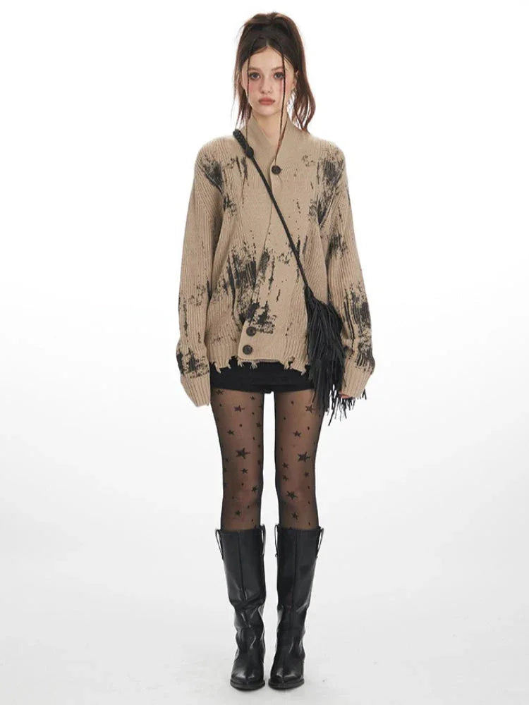 Model wearing a tan knit cardigan with abstract black print and distressed hem.