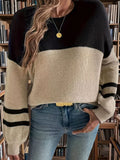 Close-up of a woman's torso wearing a black and beige striped knit sweater.