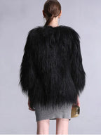 Back view of a woman wearing a black faux fur jacket and grey dress