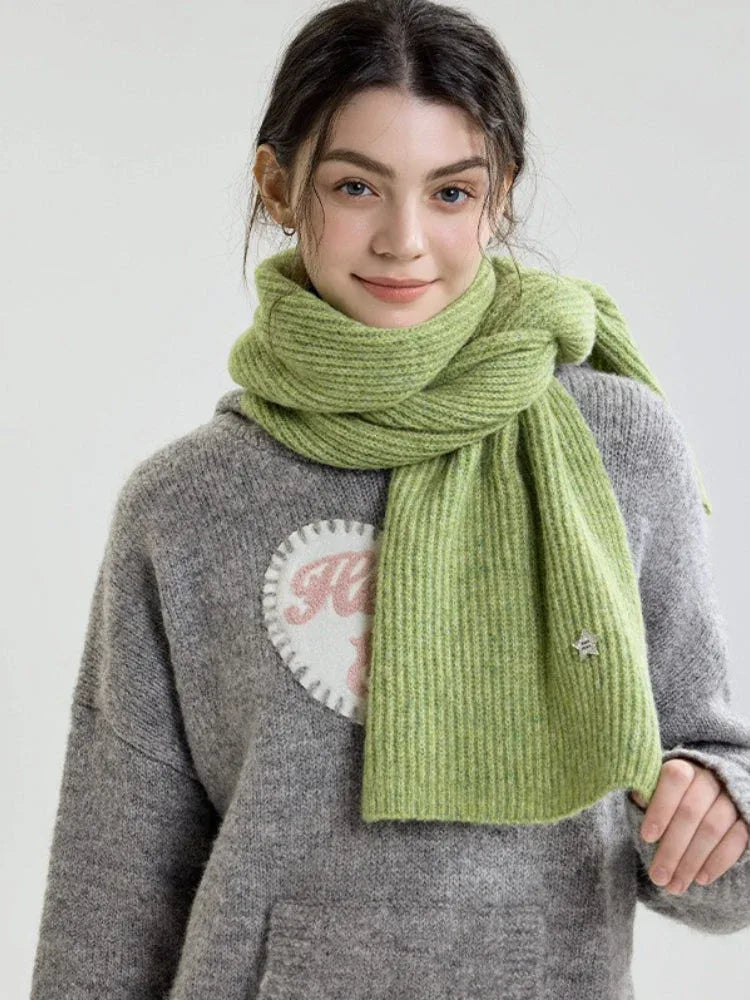 Woman modeling a light green ribbed knit scarf.