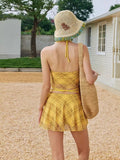 Close-up of the yellow plaid bikini top with embroidered graphic and halter neck detail.