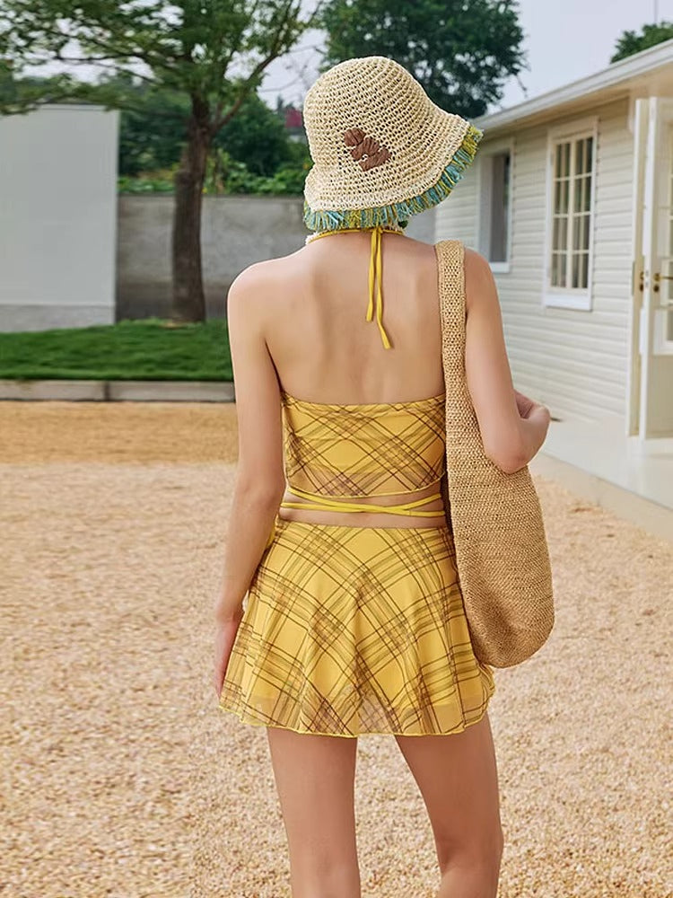 Close-up of the yellow plaid bikini top with embroidered graphic and halter neck detail.