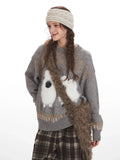Close-up of a woman wearing a grey knit sweater with a graphic sheep print, accessorized with a faux fur bag.