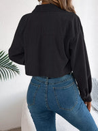 Back view of a woman in a black cropped corduroy jacket and blue jeans