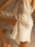 Close-up of the lace trim on the hem of a cream satin slip dress.