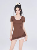 Woman wearing a brown short-sleeve swimsuit with a ruffled hem and a plaid underlayer