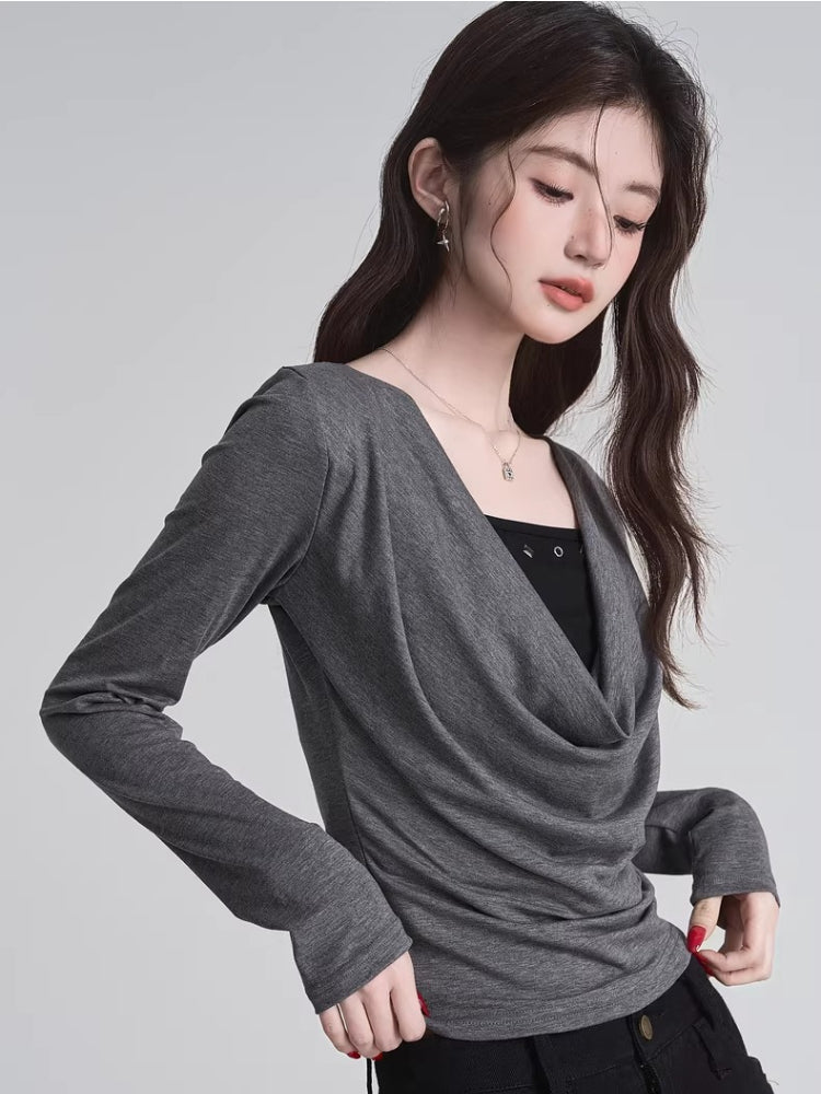 Close-up of a woman's upper body wearing a grey long-sleeve draped cowl neck top and a black camisole.