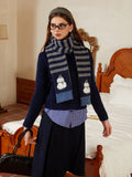 Full body shot of a woman wearing a navy knit sweater, striped scarf, and dark skirt.