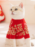 White cat wearing a red knit sweater with beige lucky fortune pattern