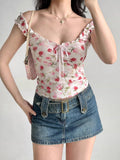 Woman wearing a white floral print top with ruffled off-the-shoulder cap sleeves and a sweetheart neckline with a pink ribbon tie, accessorized with a pink handbag and denim skirt.