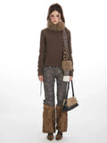 Woman wearing a brown turtleneck sweater, patterned pants with faux fur leg warmers, a leopard print scarf, and a black handbag
