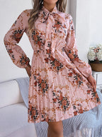 Close-up of the pink floral print midi dress with a bow neckline and pleated skirt