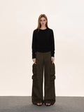 Woman wearing a black crew neck long sleeve cinched waist sweater and olive green cargo pants