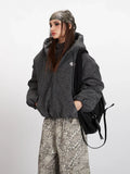 Front detail of a charcoal grey textured puffer jacket worn by a woman.