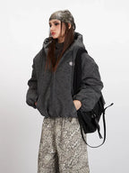 Front detail of a charcoal grey textured puffer jacket worn by a woman.