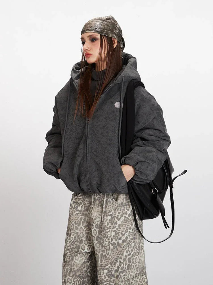 Front detail of a charcoal grey textured puffer jacket worn by a woman.