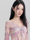 Close-up of the v-neck and tie-front detail on a lavender and peach tie-dye mesh long sleeve mini dress