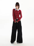 Full body shot of a woman modeling a red cable knit cardigan and black wide-leg pants.