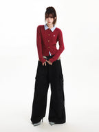 Full body shot of a woman modeling a red cable knit cardigan and black wide-leg pants.