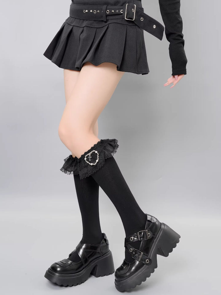 Close-up of black knit socks featuring ruffled lace edges and a metal charm.