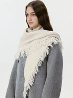 Close-up of a woman wearing a cream-colored knit scarf with fringe detail.