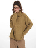 Close-up of a woman wearing an oversized camel knit sweater with a collared V-neck and button closure.