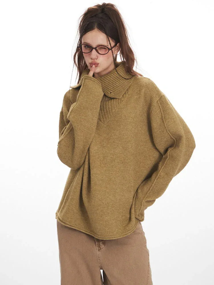 Close-up of a woman wearing an oversized camel knit sweater with a collared V-neck and button closure.