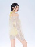 Rear view of the model in the yellow bikini and white knit cover-up.