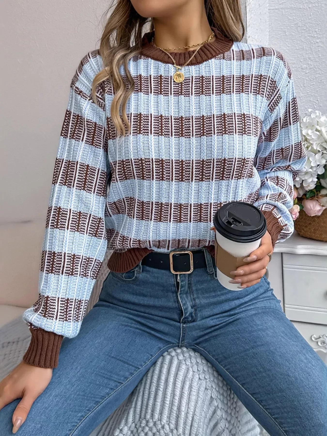 Woman in blue jeans and a striped sweater holding a coffee cup