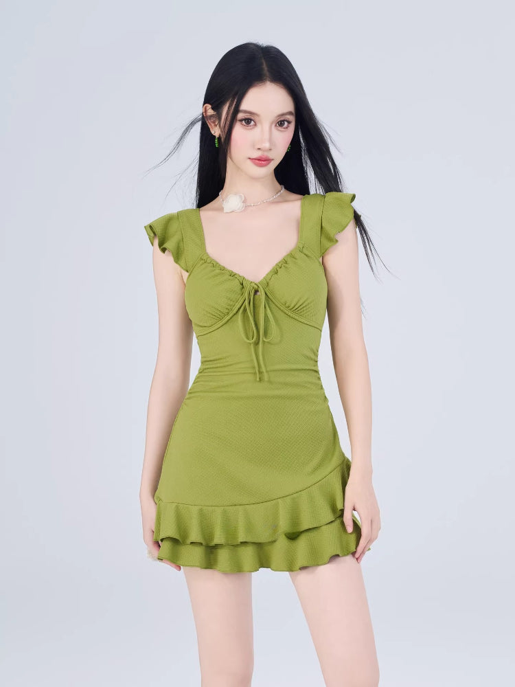 Woman wearing a lime green textured knit mini dress with ruffled flutter sleeves and a tie-front sweetheart neckline.
