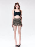Woman wearing a black camisole and a striped ruched mini skirt