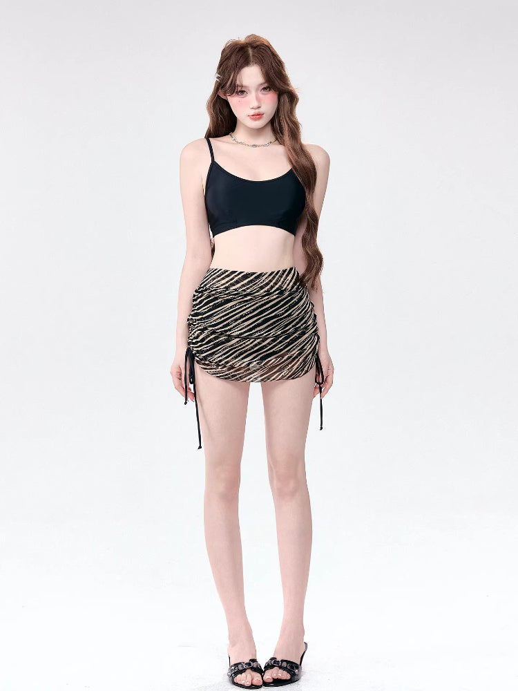 Woman wearing a black camisole and a striped ruched mini skirt
