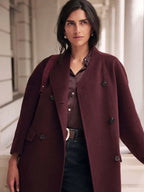 Woman wearing a burgundy double-breasted wool blend coat with dark wash jeans and a brown belt
